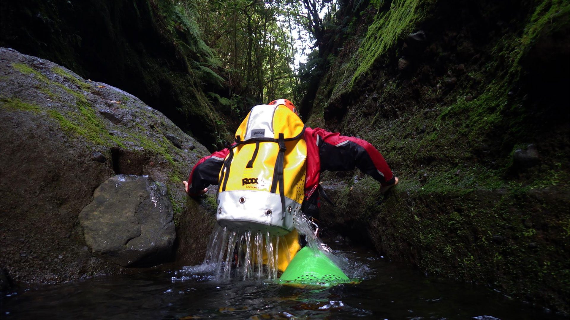 A canyoner with a canyoning backpack draining out water
